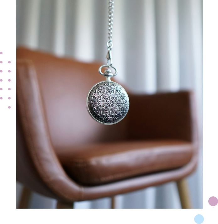 A pocket watch hanging from the side of a chair.